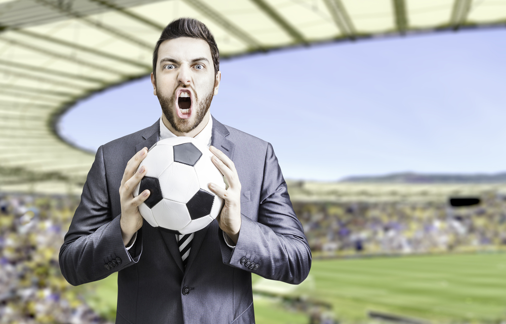 Business man holding a soccer ball celebrates in the stadium