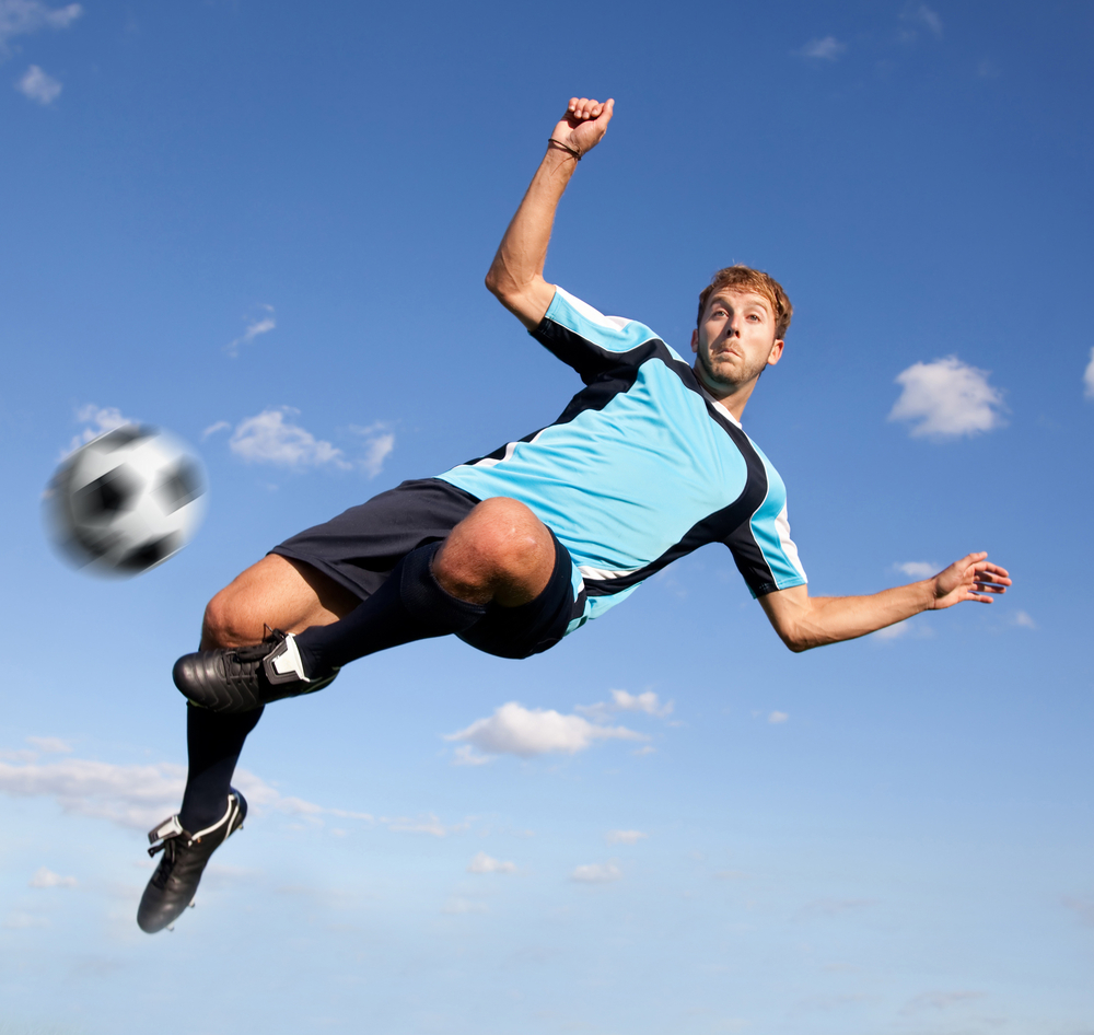 Male football player kicking the ball in the air